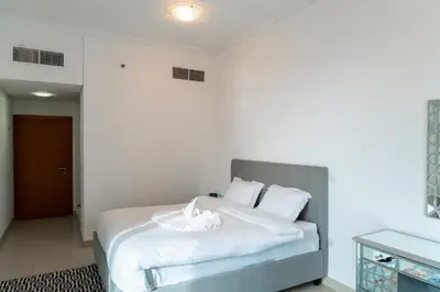 a bedroom with a bed with white sheets and pillows at Luxury 2 BHK in Ocean Heights at Dubai Marina Living with Stunning Views in Dubai