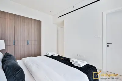 a bedroom with a bed with white sheets and slippers at 2BR Homely Apartment in Arjan in Dubai