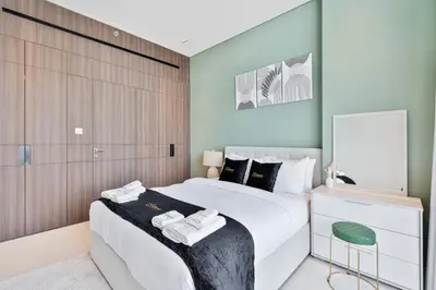 a bedroom with a large white bed and a chair at 2BR Homely Apartment in Arjan in Dubai