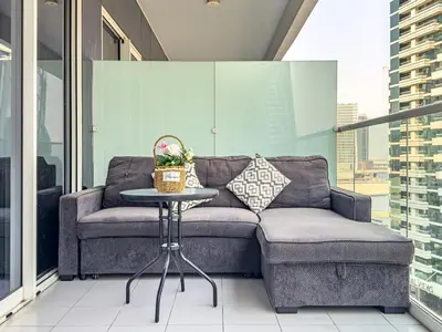 a couch sitting on a balcony with a table at Stylish 2 BR Business Bay - Canal View - Gym and Pool in Dubai