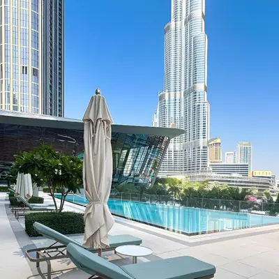 a patio with a umbrella and chairs and a pool at Burj Khalifa and Dubai Fountian Direct View - Luxury 2BR Flat - Downtown Dubai in Dubai