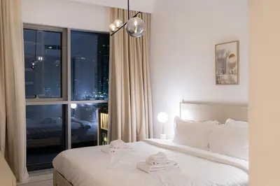 a bedroom with a bed and a large window at Seaside Bliss Chic 1BR with Balcony, Pool & Gym in Dubai