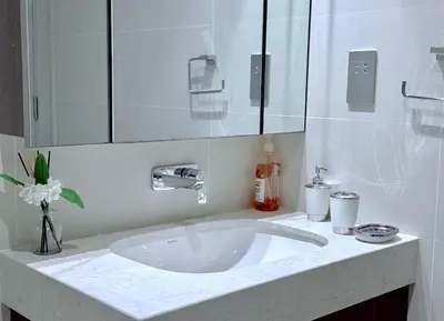 a white bathroom with a sink and a mirror at Seaside Bliss Chic 1BR with Balcony, Pool & Gym in Dubai