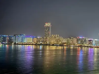 a view of a city at night from the water at Seaside Bliss Chic 1BR with Balcony, Pool & Gym in Dubai