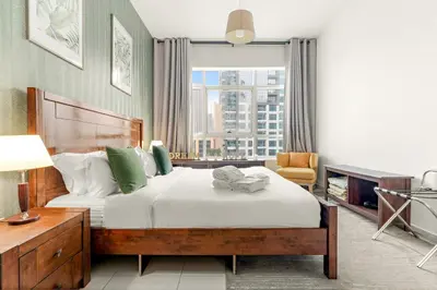 a bedroom with a bed and a large window at Stylish 1BR - Pool, Gym Access & City Skyline Views near JBR Beach in Dubai
