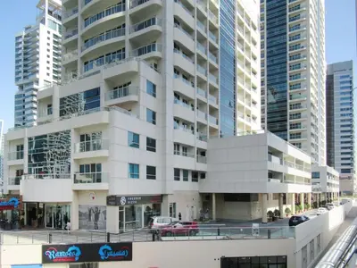 a large white building in a city with tall buildings at Stylish 1BR - Pool, Gym Access & City Skyline Views near JBR Beach in Dubai