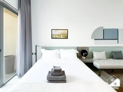 a bedroom with a white bed and a couch at Modern Studio Retreat l MAG l Parking & WI-FI in Dubai