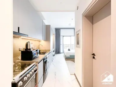 a kitchen with white cabinets and a stove at Stylish Studio Living l MAG Meydan in Dubai