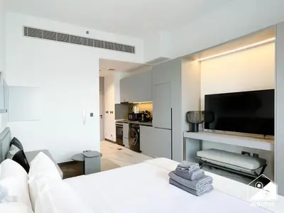 a living room with a white couch and a flat screen tv at Stylish Studio Living l MAG Meydan in Dubai