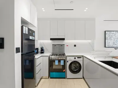 a white kitchen with a washing machine and a washer at Chic and Stylish 1 BDR in Binghatti corner - JVC in Dubai