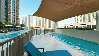 a swimming pool with chairs and an umbrella on a balcony at Modern Creekside 1BR Near Dubai Mall & Downtown in Dubai