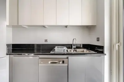 a kitchen with white cabinets and a sink at Stylish 1BR with Burj & Canal View in Dubai