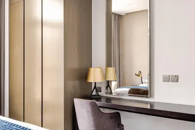 a bedroom with a mirror and a bed and a chair at Stylish 1BR with Burj & Canal View in Dubai