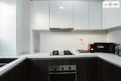 a kitchen with white cabinets and a stove top oven at Serenity 1 bdr with private garden in Dubai