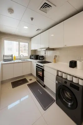 a kitchen with a washer and dryer in it at Premium 1BR, 2 Bath, Walk to Circle Mall, Pool & Gym in Dubai