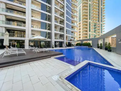 a large building with a swimming pool in front of a building at Space, Style & Sunshine 2bedroom in Dubai