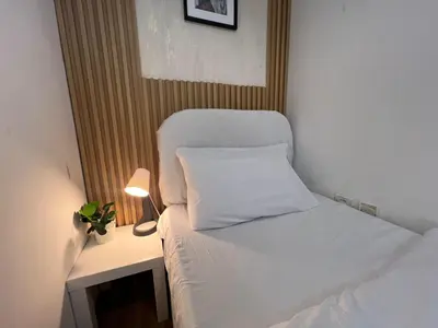 a small bedroom with a white bed and a lamp at Minimalist Room In Al Barsha 1 Near Mall of Emirates in Dubai