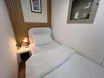 a small room with two beds and a chair at Minimalist Room In Al Barsha 1 Near Mall of Emirates in Dubai