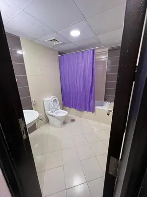 a bathroom with a toilet and a purple shower curtain at Deluxe solo Room In Barsha Heights Tecom in Dubai