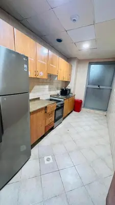 a kitchen with wooden cabinets and a stainless steel refrigerator at Cozy Barsha Spot In Barsha 1 in Dubai