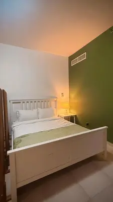 a bed in a room with a green wall at Studio-Like Private Bedroom with Balcony & Private Washroom in JLT in Dubai