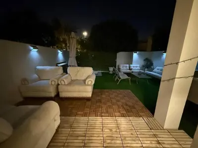 two white couches sitting on a patio at night at Luxe 4BR Villa with Park View - Next to Pool Oasis - Ranches 3 - Sleep 10 in Dubai