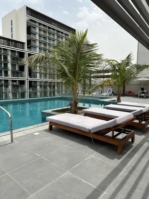 a swimming pool with several beds next to a building at LUXE - Luxury Studio - Modern and Cozy in Dubai