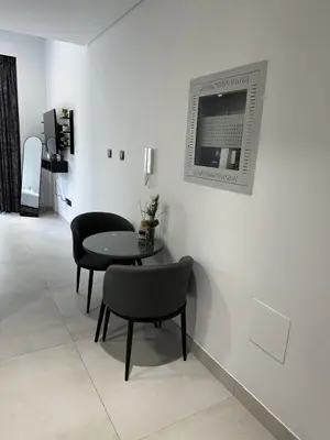 a white room with a table and chairs and a television at LUXE - Luxury Studio - Modern and Cozy in Dubai