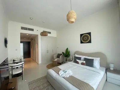 a bedroom with a bed and a desk and a room at Modern DAMAC Hills Studio with Balcony, Gym & Pool in Dubai