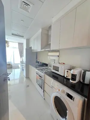 a kitchen with a stove and a washer and dryer at Modern DAMAC Hills Studio with Balcony, Gym & Pool in Dubai