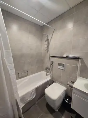 a bathroom with a tub and a toilet and a sink at Modern DAMAC Hills Studio with Balcony, Gym & Pool in Dubai