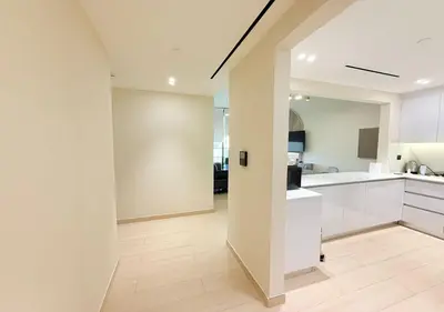 an open kitchen with white cabinets and a hallway at Binghatti Crescent Cozy 2 BR in Dubai