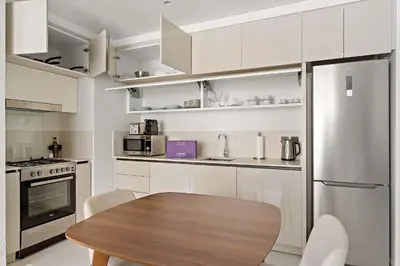 a kitchen with white cabinets and a wooden table at Silkhaus Seaside Bliss 1BDR in Marina Vista in Dubai