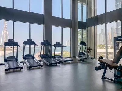a gym with several treadmills in a building with windows at Sunset Sea View at 5242 Emaar in Dubai