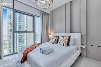 a bedroom with a white bed with a large window at bnbmehomes - Downtown Views II in Dubai