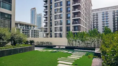 a park with a bench in a city with tall buildings at Beautiful Brand New Studio -Pool -Balcony -Parking in Dubai