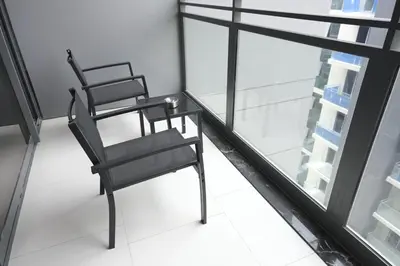 a black chair sitting next to a glass table at Beautiful Brand New Studio -Pool -Balcony -Parking in Dubai
