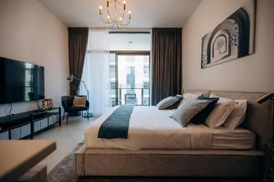 a bedroom with a large bed and a living room at Beautiful Brand New Studio -Pool -Balcony -Parking in Dubai