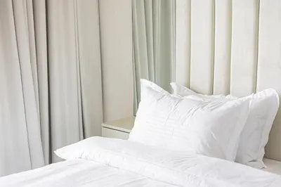 a bed with white sheets and pillows next to a window at Luxury 3BR Palm Views at Emaar Beachfront in Dubai