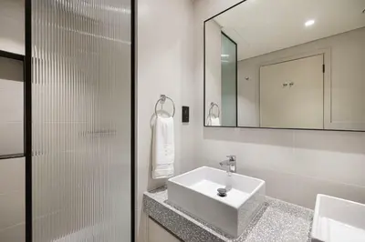 a white bathroom with a sink and a mirror at Luxury 3BR Palm Views at Emaar Beachfront in Dubai