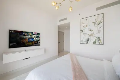 a white bedroom with a flat screen tv on the wall at Luxury 3BR Palm Views at Emaar Beachfront in Dubai