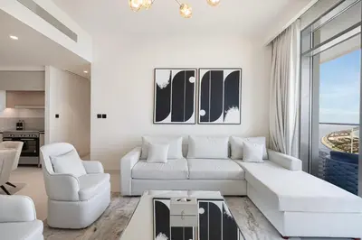 a living room with a white couch and chairs at Luxury 3BR Palm Views at Emaar Beachfront in Dubai