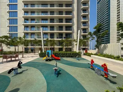 a playground in front of a tall building at Luxury 3BR Palm Views at Emaar Beachfront in Dubai