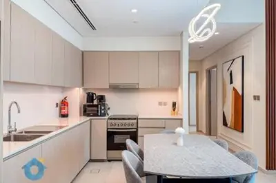 a kitchen with white cabinets and a table with chairs at Next to Burj Khalifa & Dubai Mall - Luxury 2BR with Dubai Skyline Views - Like Home in Dubai
