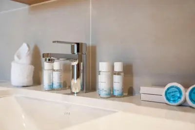a bathroom sink with a faucet and toiletries on a shelf at Ultra Luxuary 2BR - Creek Beach - Serenity Living in Dubai