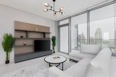 a living room with a white couch and a tv at Bespoke Holiday Homes - Luxury 2BR with Stunning Marina Views in LIV Marina in Dubai