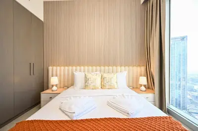 a bedroom with a bed with two lamps and a window at Luxury 2BR in Downtown 35th Floor 5 min walk Dubai Mall, Gym,Pool, 500mbps Wifi, Forte Tower in Dubai