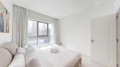 a white living room with a white couch and a window at The Point - One Bed with Marina Skyline Views in Dubai