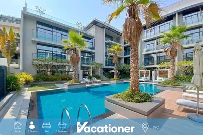 a view of a building with a swimming pool and palm trees at Oxford Boulevard - Vibrant Studio in JVC in Dubai