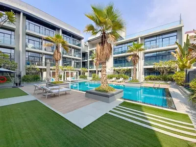 an apartment building with a swimming pool and palm trees at Oxford Boulevard - Vibrant Studio in JVC in Dubai